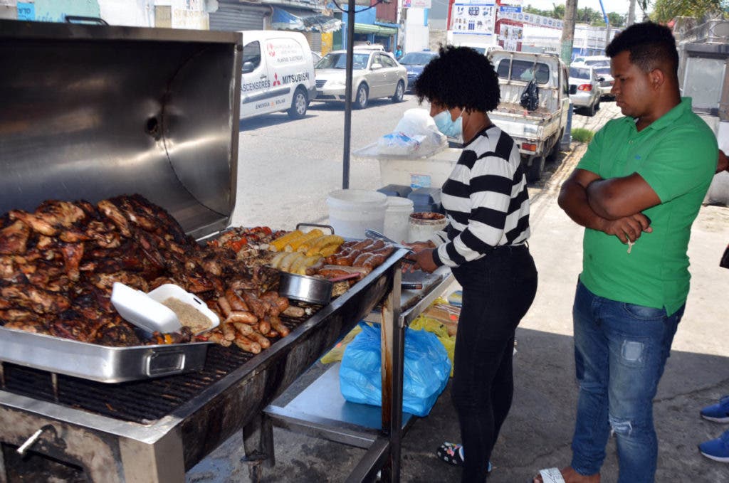 Una mujer oferta chuletas de cerdo en una pequeña fritura, negocios que han sido afectados tras la presencia en el país de la peste porcina africana.