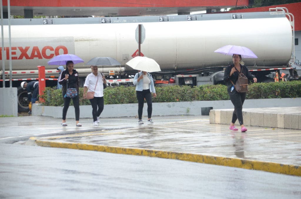 Varias personas caminan con sombrillas para protegerse de la lluvia que se registra en el país debido a una vaguada