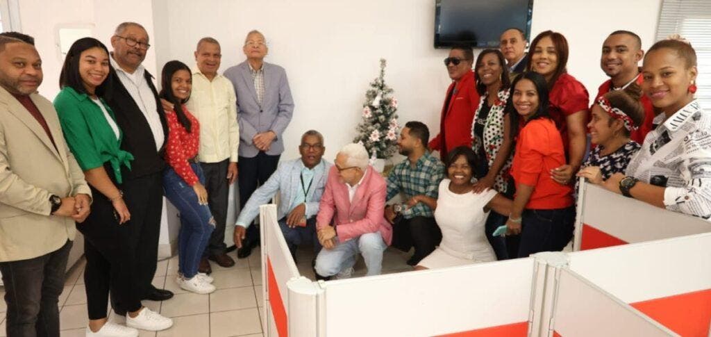 El director de El Nacional, Bolívar Díaz Gómez, y el merenguero Kinito Méndez, encienden el arbolito de Navidad de la redacción junto a periodistas del medio.