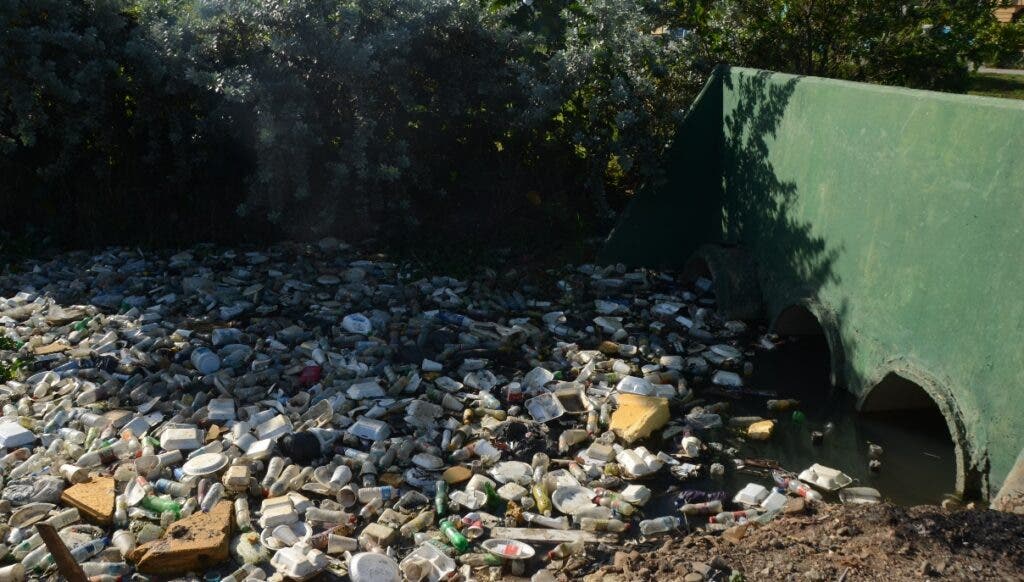 Los desechos plásticos que llegan a través de las alcantarillas al río Ozama se quedan atrapados hasta que el afluente reciba agua. Foto Jorge González