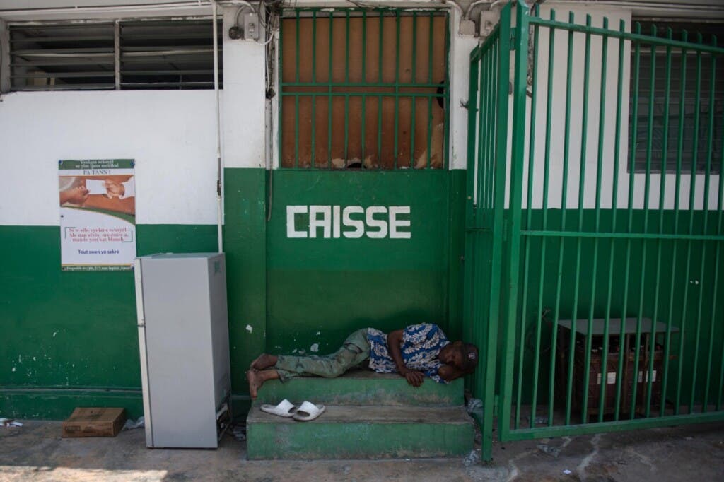 Un hombre duerme junto al Hospital Universitario Estatal de Haití, recinto que fue abandonado desde hace cerca de un mes, este martes en Puerto Príncipe (Haití). El centro de Puerto Príncipe ha quedado abandonado a manos de las bandas armadas y ni siquiera la Policía acude ya a la zona, en una ciudad donde este martes hay farmacias, clínicas o escuelas atacadas e incendiadas, pese al estado de emergencia en vigor y el toque de queda prorrogado hoy. Los alrededores del Hospital Universitario Estatal de Haití, abandonado desde hace cerca de un mes, fueron blanco de los grupos armados pertenecientes a la coalición 'Vivre Ensemble' ('Vivir juntos'), que encabeza el poderoso Jimmy Cherizier, alias Barbecue. EFE/ Johnson Sabin