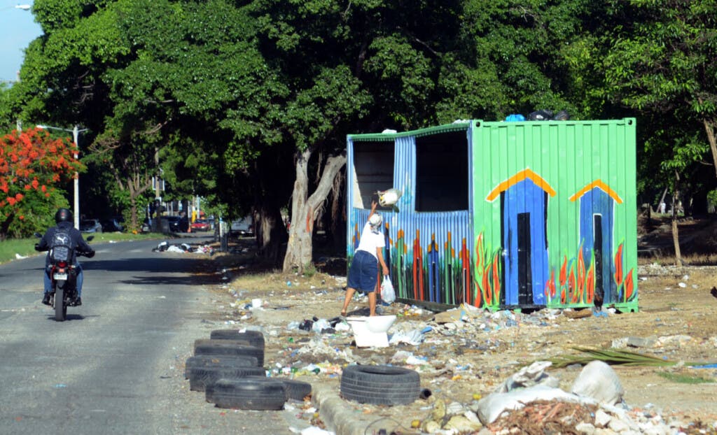 Una señora deposita dos fundas de basura en uno de los contenedores.