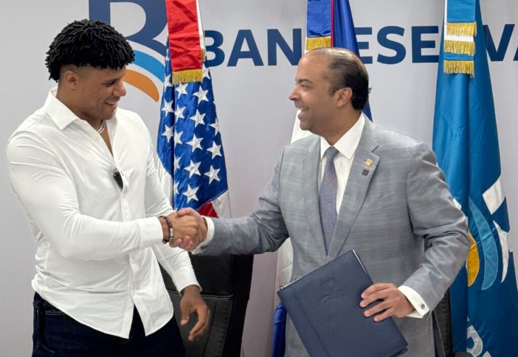 Juan Soto, la superestrella de los Mets de Nueva York y el licenciado Samuel Pereyra Rojas, presidente ejecutivo de Banreservas, se saludan sorientes tras firmar el convenio.