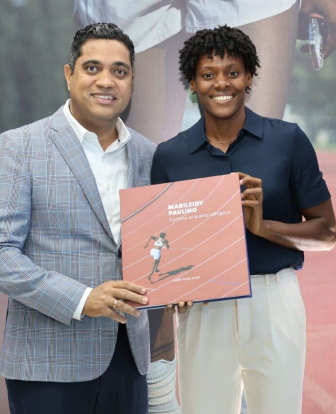 El ministro de Deportes, Kelvin Cruz, recibe el libro de Marileidy Paulino en el que se resaltan varios de sus triunfos.
