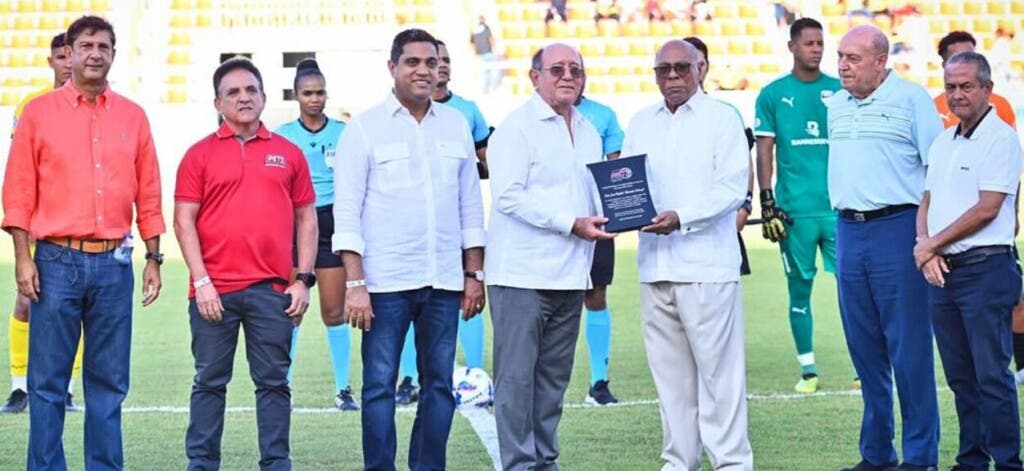 El doctor Milton Ray Guevara, presidente de la LDF,  entrega una placa a Reynaldo Salcedo, vicerrector de O&M, quien representó a la familia del  fenecido doctor José Rafael Abinader. Desde la izquierda, Manuel Estrella, Esteban Ferreiras, Kelvin Cruz, el padre Eulogio y José Dechamps.