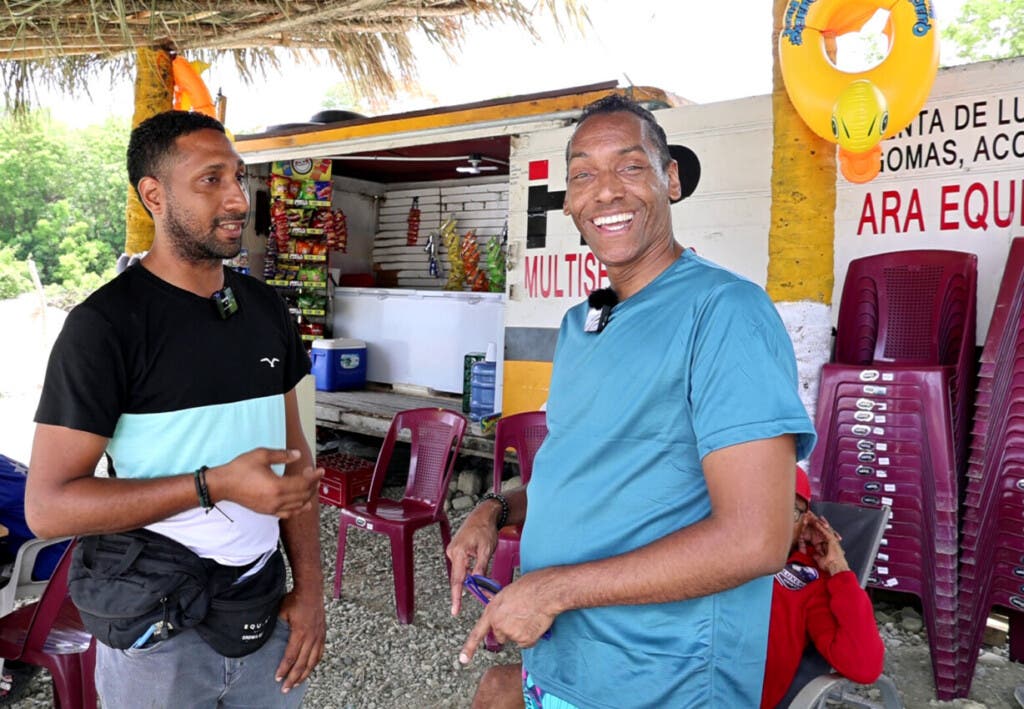 El periodista Lázaro Medina (d) conversa con el señor Junior, administrador del negocio La Esquina dominicana en Los 3 Charquitos, Pizarrete. / Duany Núñez.