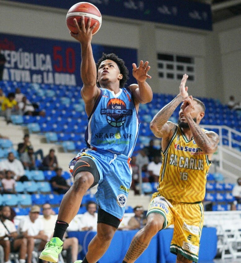 Eddy Mercedes llega hasta al aro, perseguido por Jaison Valdez