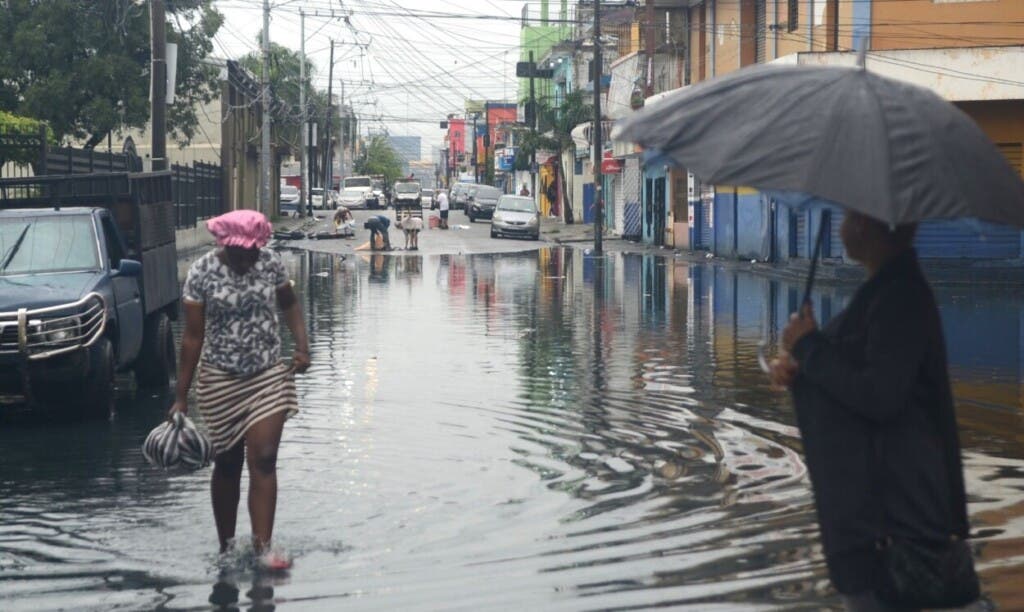 Una mujer camina entre el agua acumulada en una calle del Gran Santo Domingo producto de las lluvias de la tormenta Melissa./Foto Jorge González