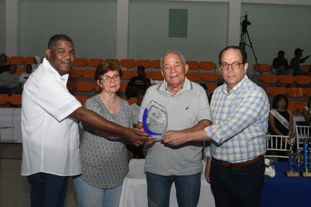 Fausto Severino, acompañado de su esposa, Sandra Gómez, recibe una placa de reconocimiento de Franklin De La Mota, viceministro de Deportes y  Primitivo Cadete,  directivo  de la Federación Dominicana de Boxeo.