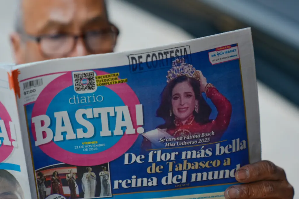 Una persona lee un periódico con la noticia en primera plana de que la mexicana Fátima Bosch ganó el título de Miss Universo 2025, en la Ciudad de México, el viernes 21 de noviembre de 2025. (Foto AP/Marco Ugarte)