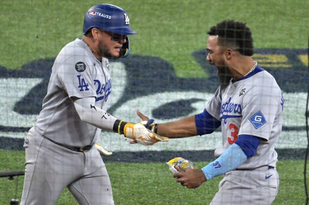 El dominicano Teoscar Hernández saluda al venezolano Miguel Rojas tras conectar el jonrón que empató el partido 4-4 entre Los Dodgers y Toronto en la novena entrada
