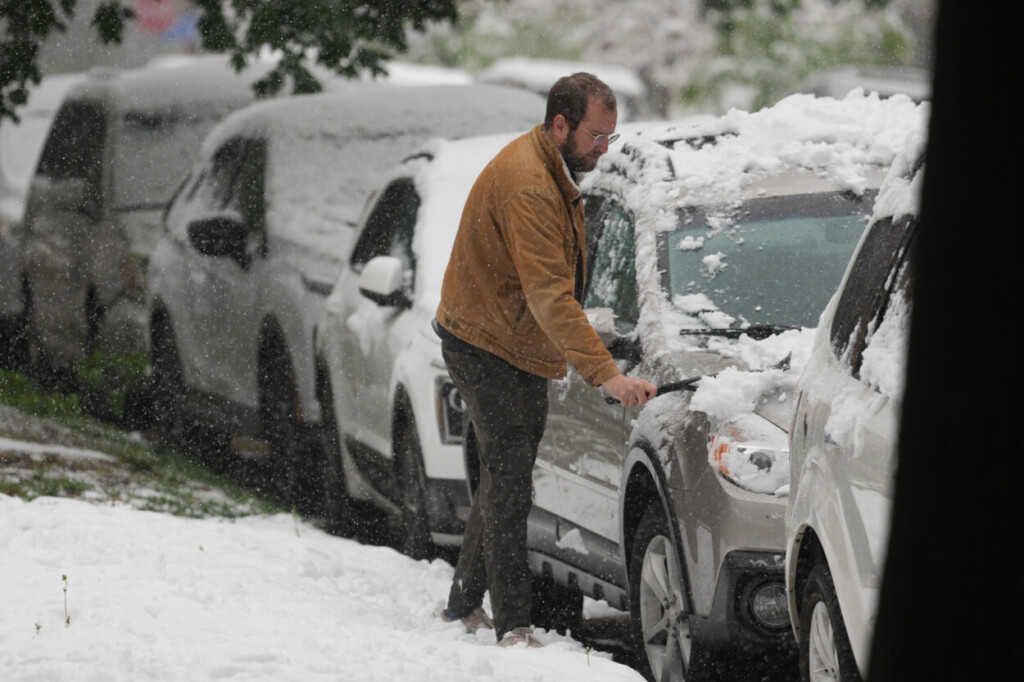 Un automovilista retira la nieve de un vehículo utilitario mientras una tormenta primaveral con bajas temperaturas y nieve azota la región intermontañosa del oeste, el miércoles 6 de mayo de 2026, en Denver. (Foto AP/David Zalubowski)