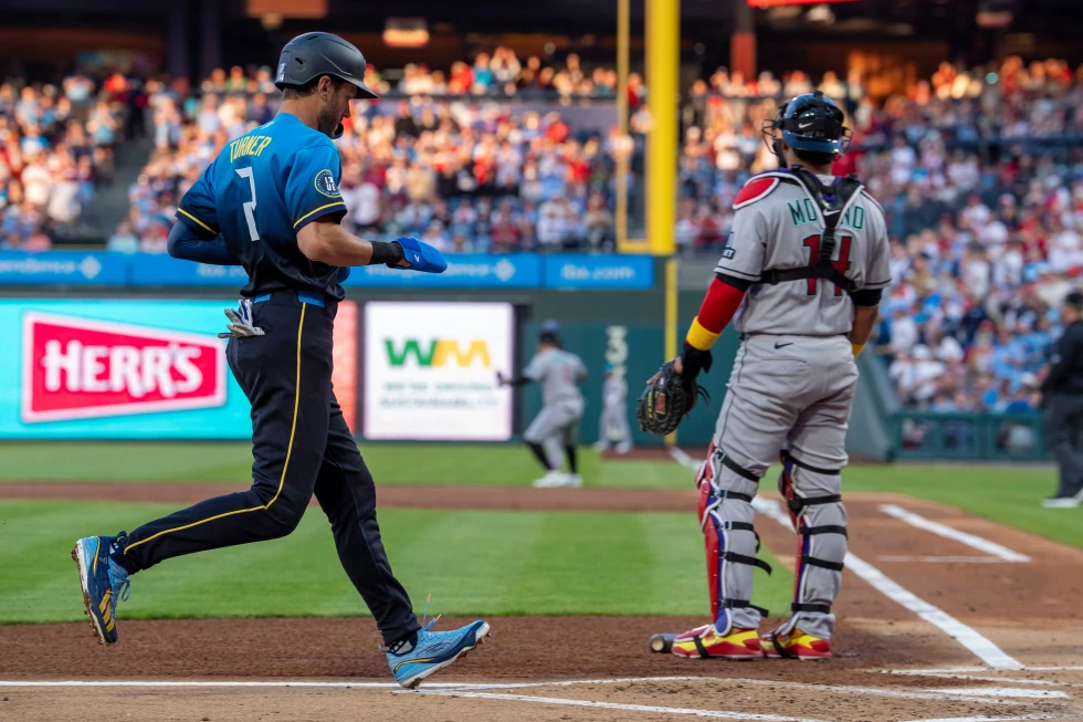 Trea Turner, de los Philadelphia Phillies (izquierda), anota tras un doble de Bryce Harper, mientras el receptor de los Arizona Diamondbacks, Gabriel Moreno (derecha), observa durante la primera entrada de un partido de béisbol, el viernes 10 de abril de 2026, en Filadelfia. (Foto AP/Chris Szagola)